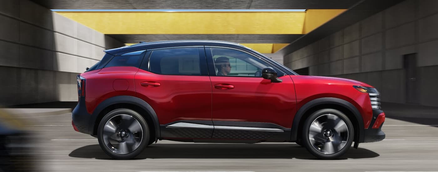 Side of a red 2026 Nissan Kicks driving on a highway