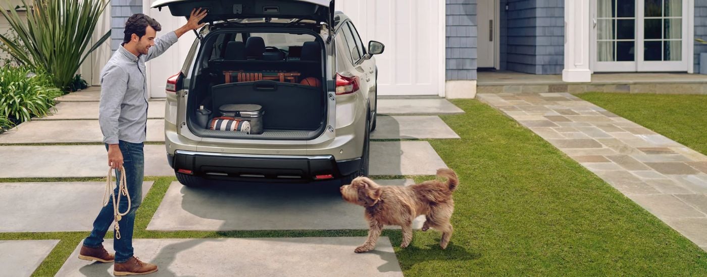 Tan 2026 Nissan Rogue in a driveway with a man and dog.