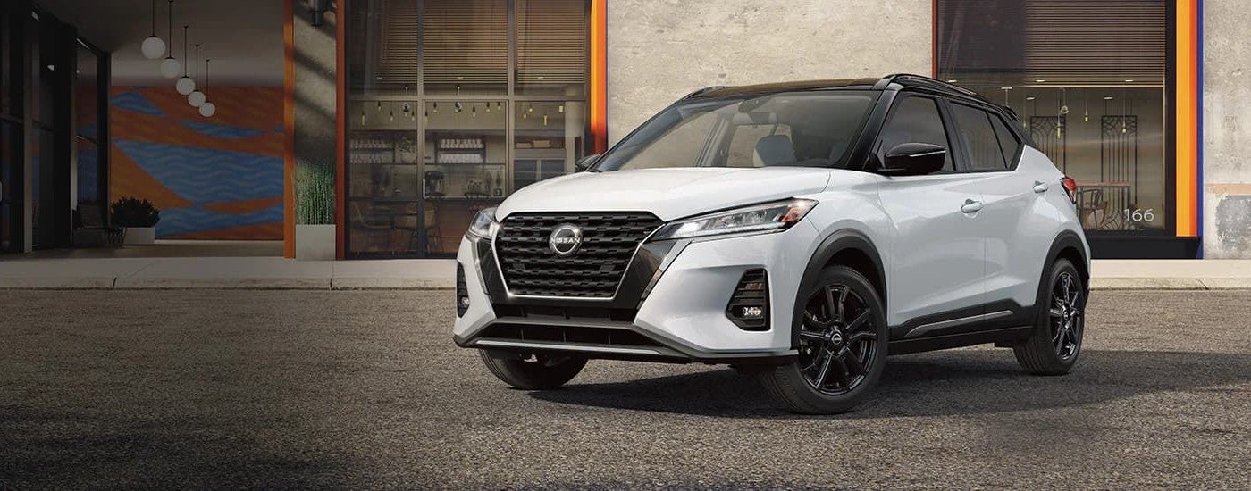 A white 2023 Nissan Kicks parked by a building.