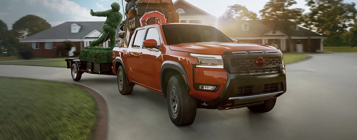 An orange 2026 Nissan Frontier towing a trailer.