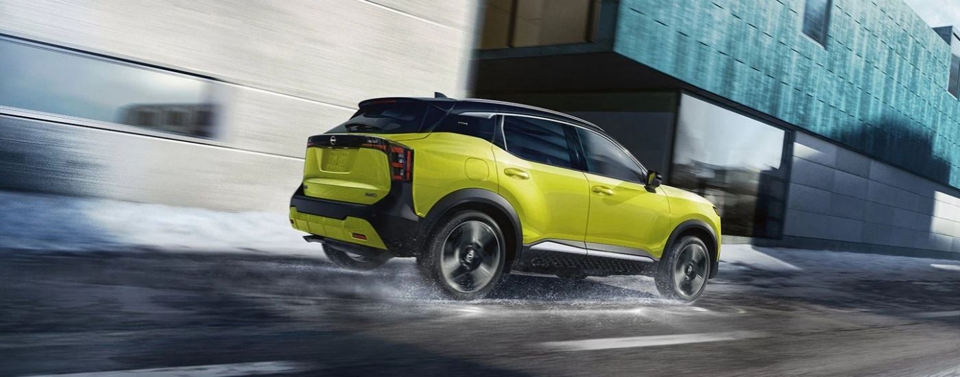 Rear view of a yellow 2027 Nissan Kicks SR driving a wet road. 