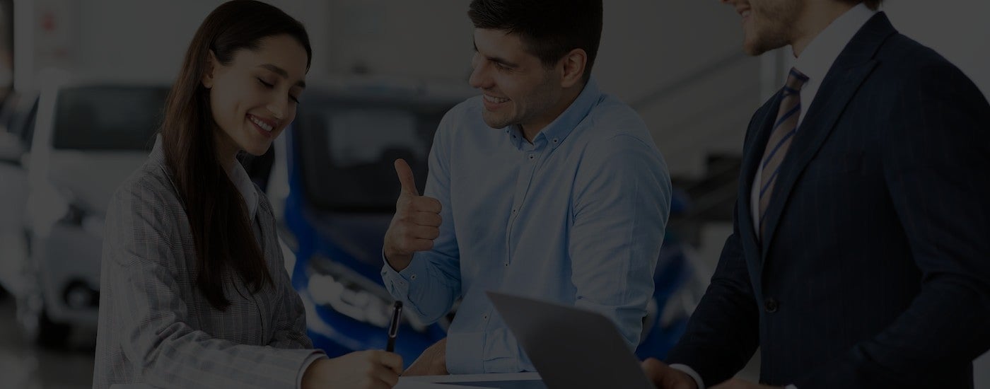 Two salespeople working with a customer on financing paperwork